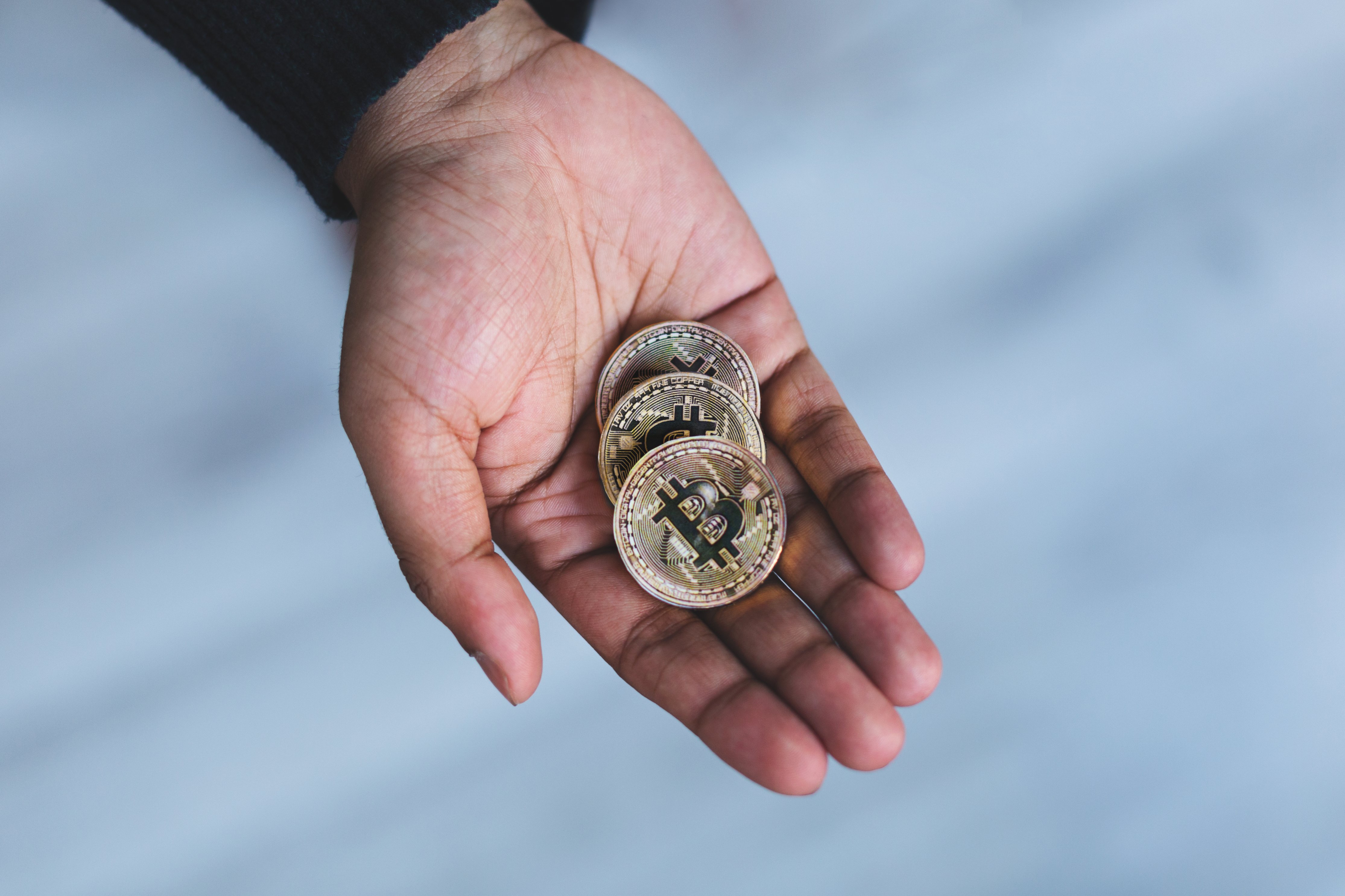 Crypto investor holding three gold btc-coins